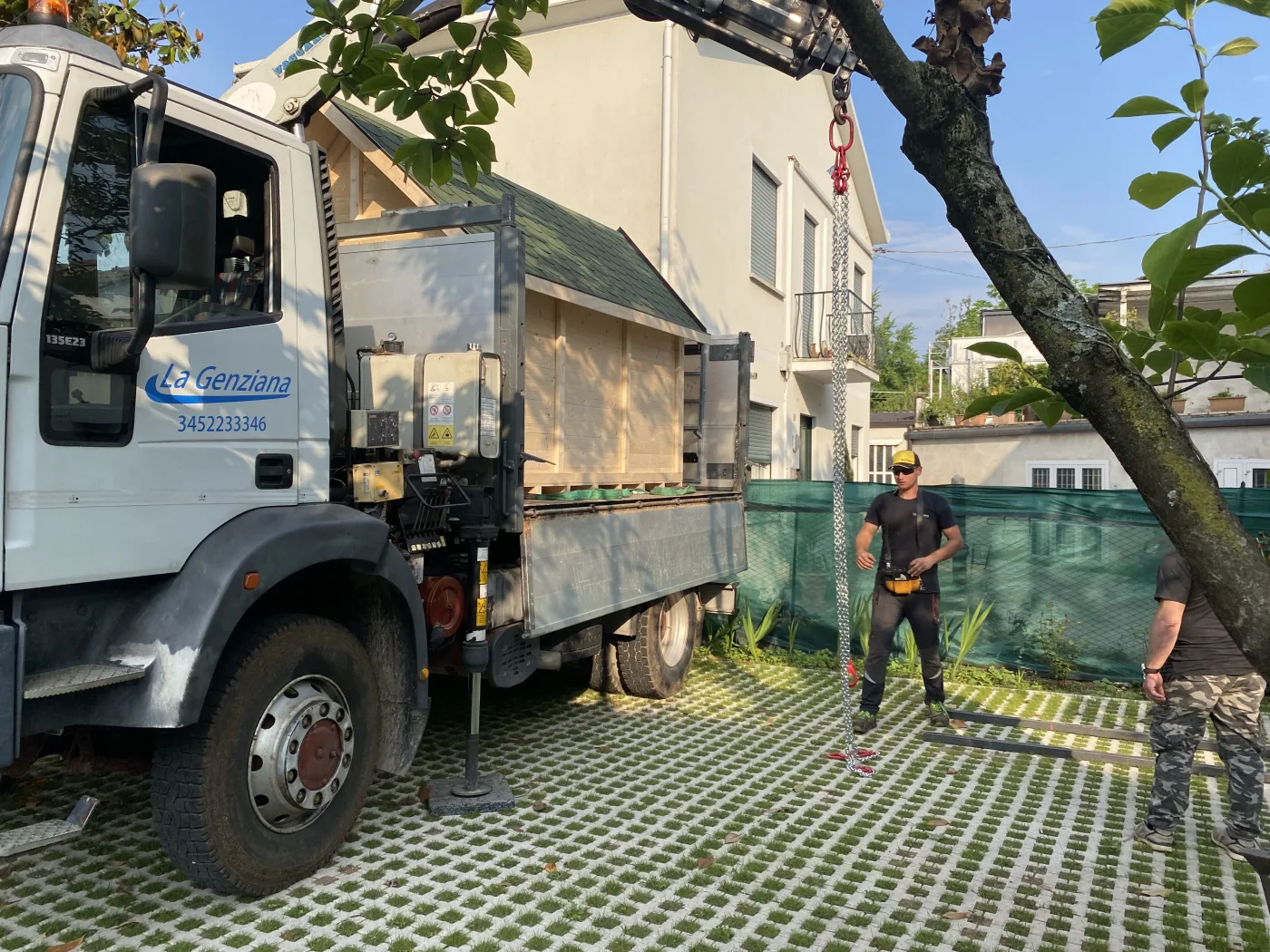 Consegna e installazione di una grande casetta con camion e operai.