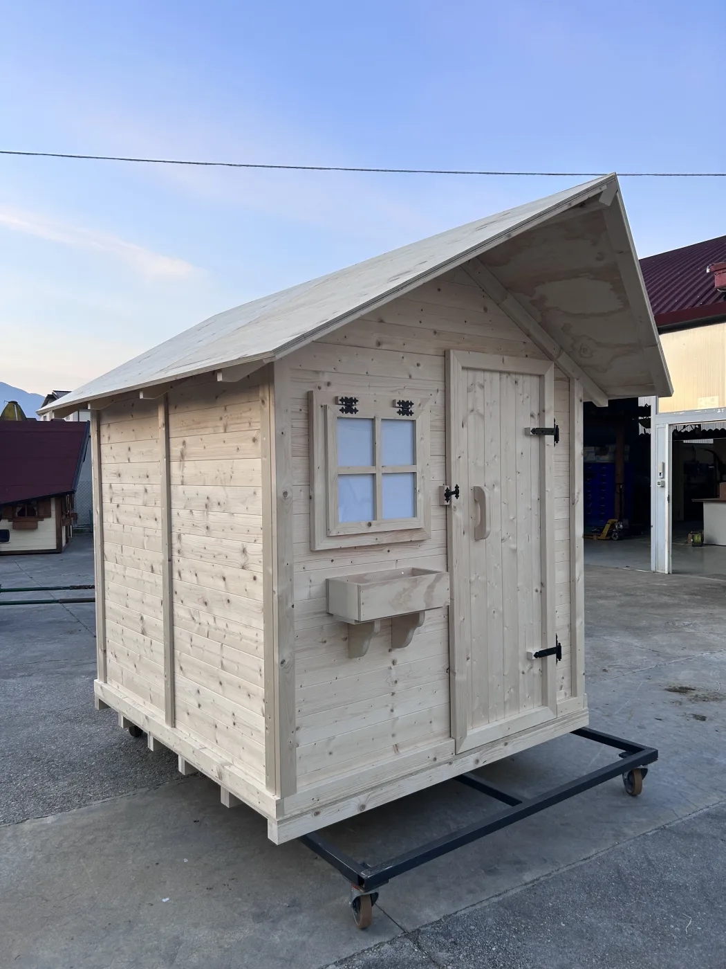 Casetta in legno naturale grezzo su carrello a ruote, pronta per la consegna.