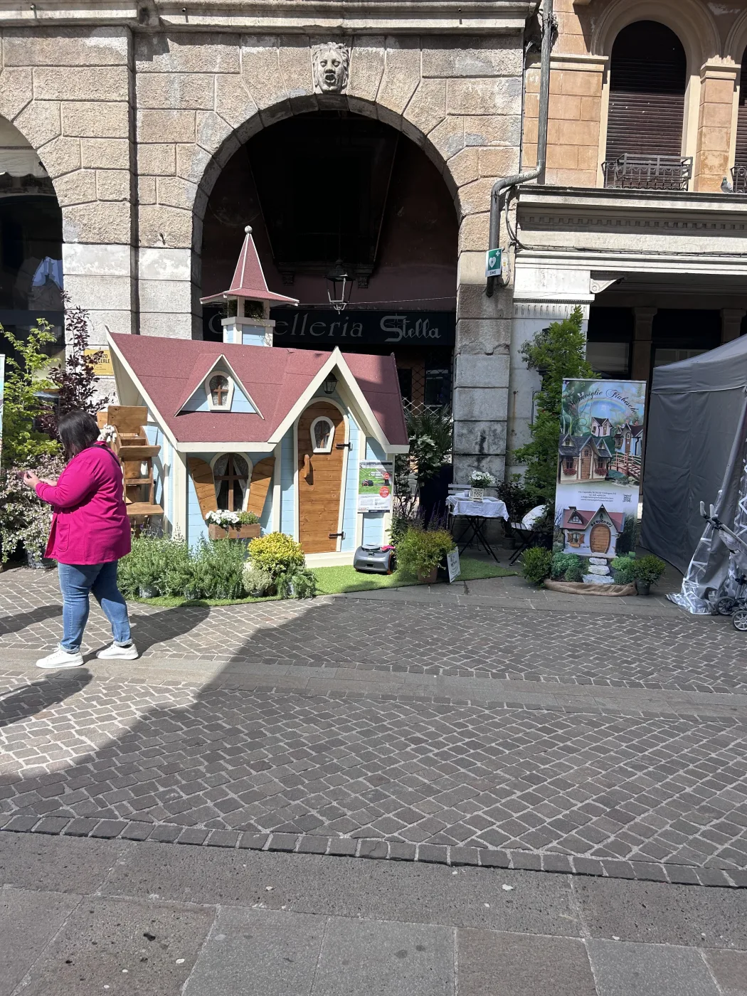 Casetta azzurra con campanile esposta in piazza storica sotto i portici.