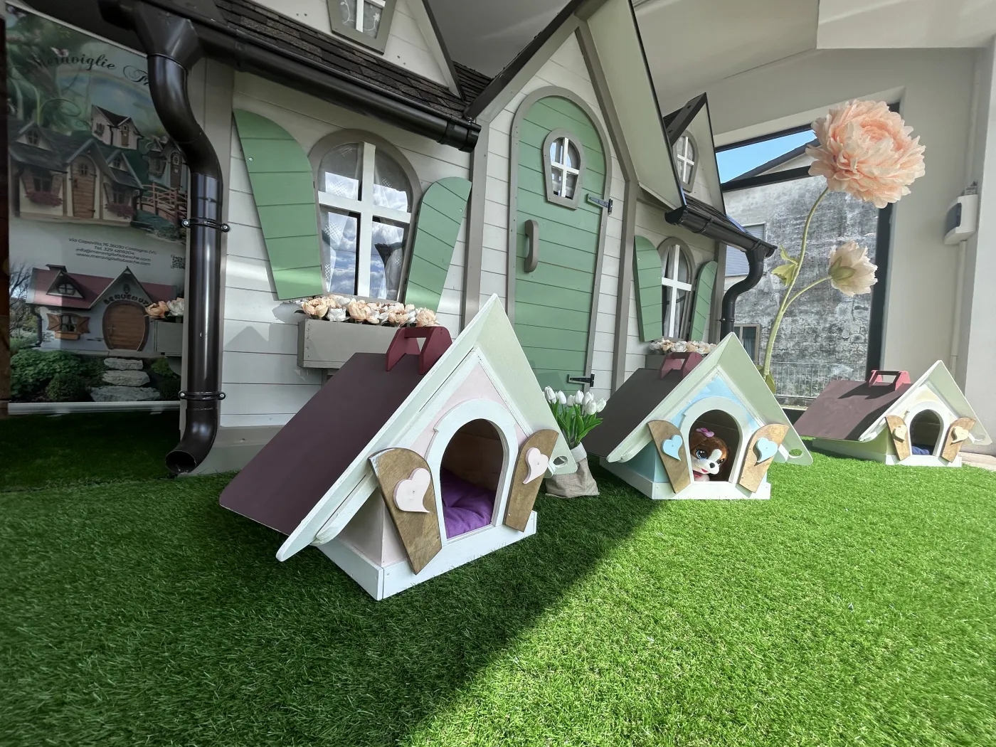 Cucce per animali in legno all'interno dello showroom con grande casetta verde.