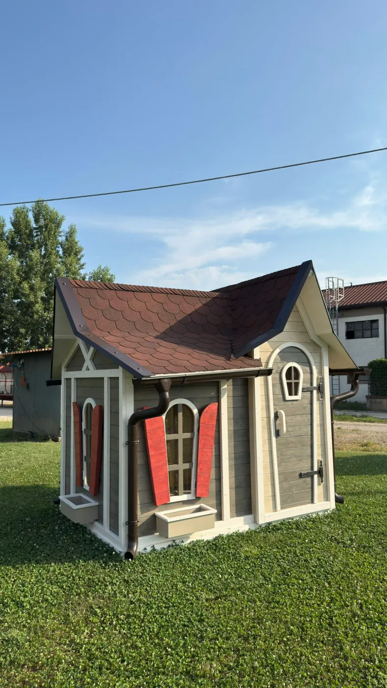 Antico carro con una grande botte di legno in primo piano, davanti alla casetta a tenda color tortora.