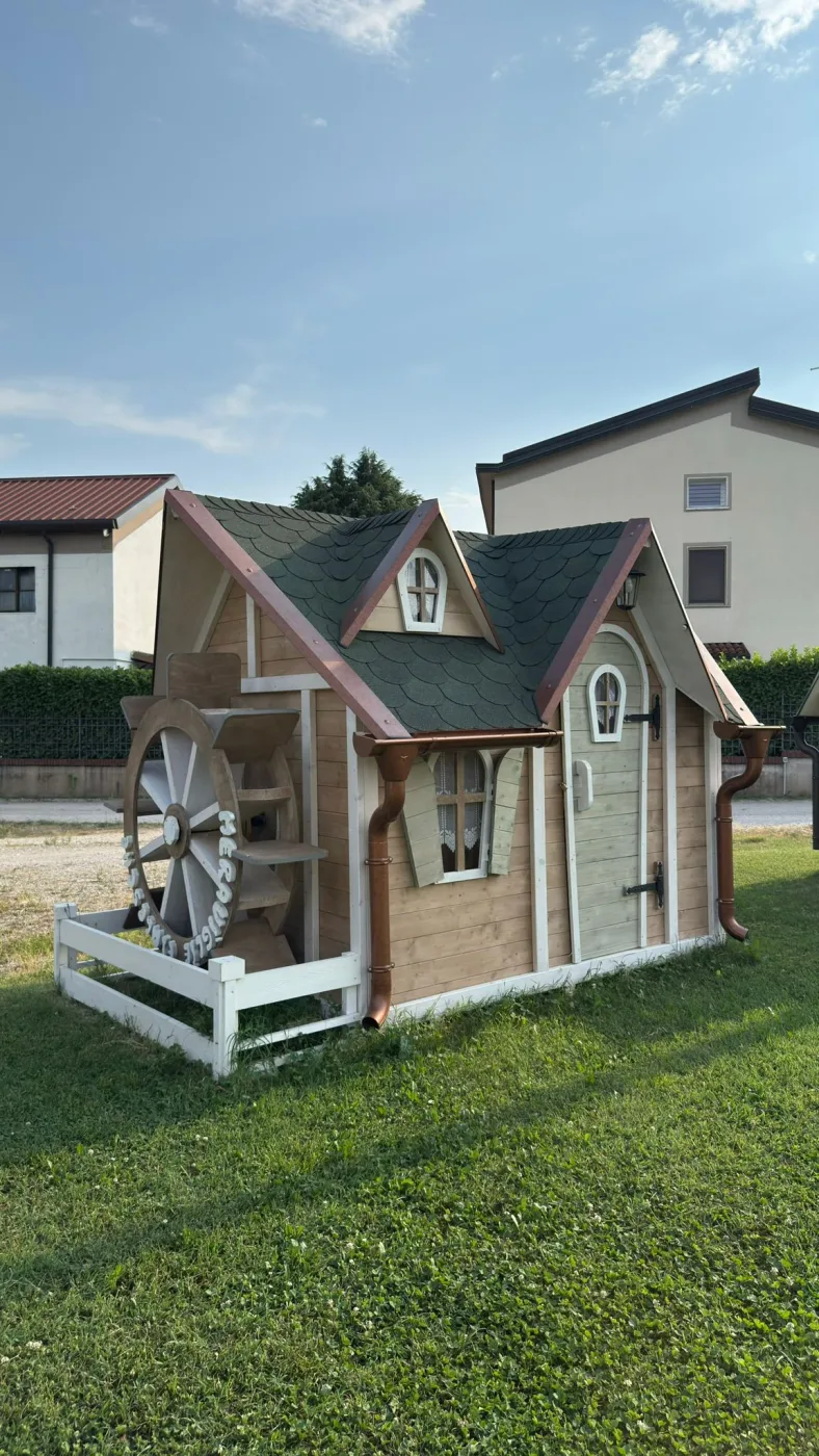 Casetta a tenda con il tetto sollevato per mostrare la struttura interna, comignolo con scaletta a pioli e finestra rotonda.