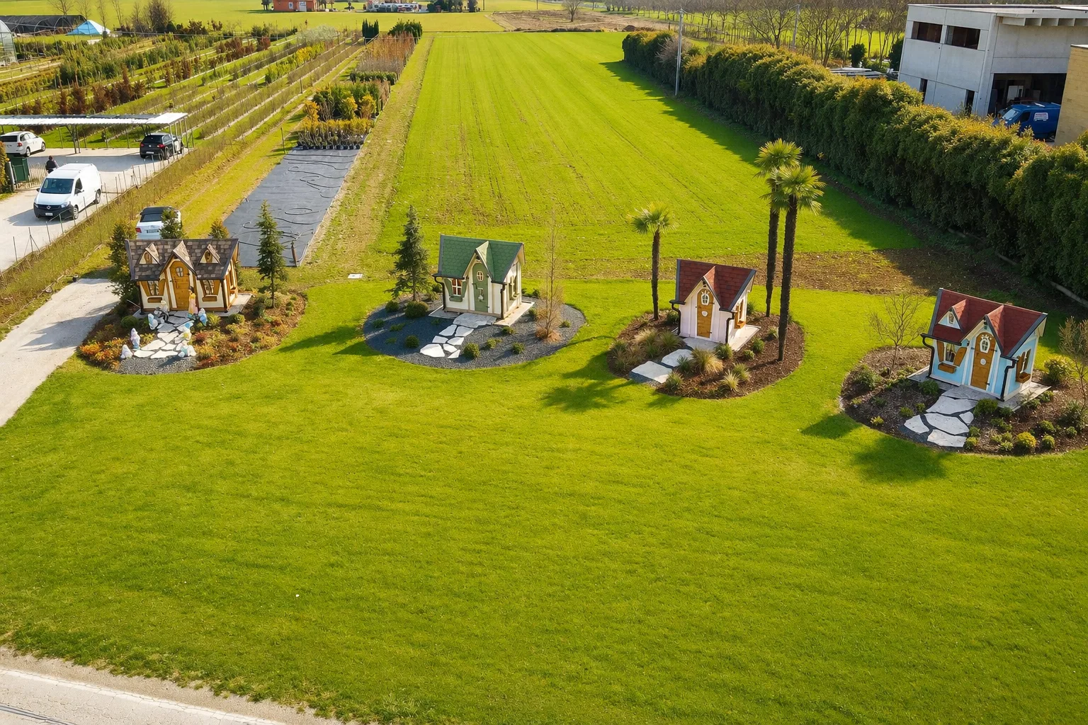 Vista aerea con drone delle quattro casette in legno disposte tra le aiuole nel prato verde dello showroom di Thiene.
